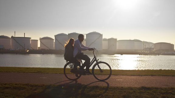 Man fietst door de haven met vrouw achterop