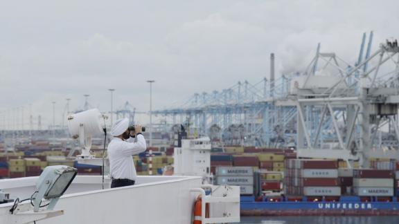 Expats in Rotterdam, kapitein op brug kijkt door verrekijker richting land