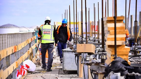 Zwei Männer arbeiten an der Errichtung von Windschutzvorrichtungen als Teil des Theemswegtracé