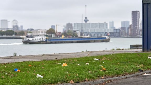 Binnenvaartschip in de Waalhaven in Rotterdam met op de voorgrond een grasveld met zwerfafval