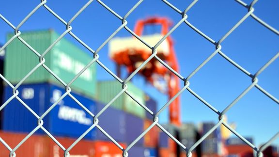 Container hinter einem Zaun zur Kennzeichnung der Hafensicherheit