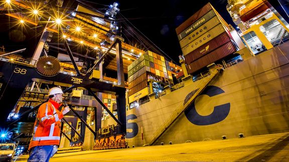 Employee with walkie-talkie near container ship