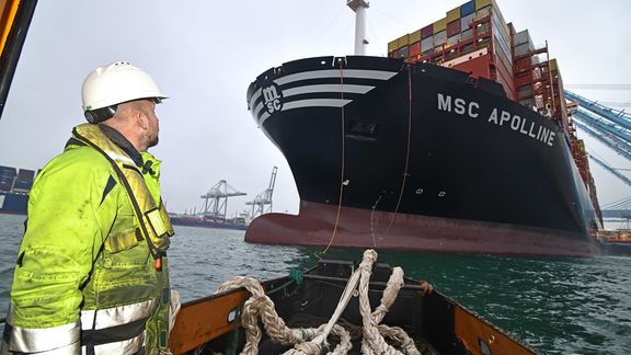 Oarsmen haul in the mooring lines of MSC Apolline