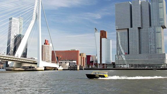 Watertaxi sails on the Nieuwe Maas in front of the Erasmusbridge