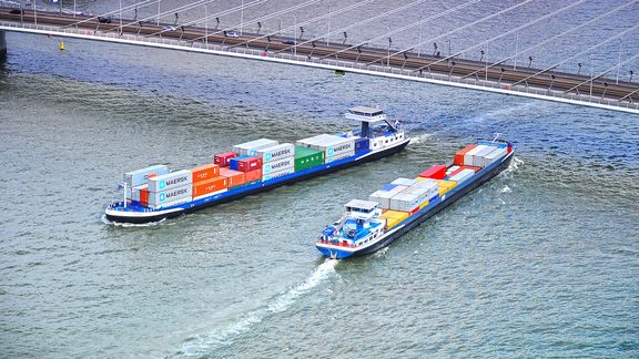 Two inland ships pass eachother under the Erasmus Bridge