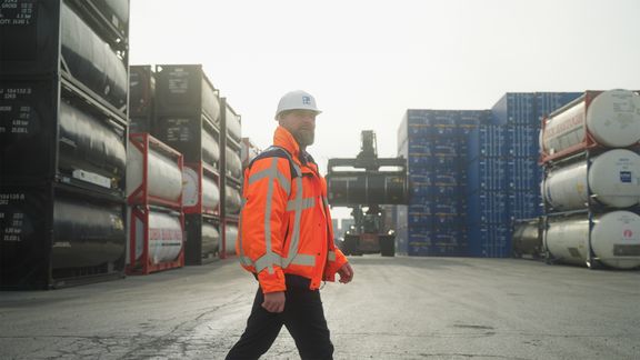 Ron Kuijpers bei einem Spaziergang über das Gelände von Broekman Logistics, mit Chemikalienbehältern im Hintergrund