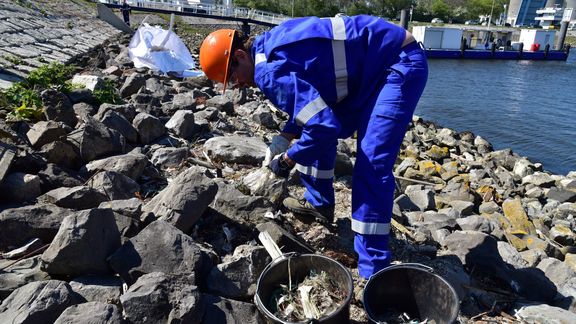 Man ruimt plastic op langs de waterkant