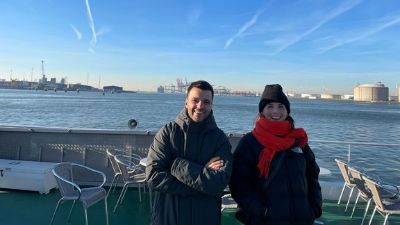 Kenzo en Emily op dek van schip met op de achtergrond de haven