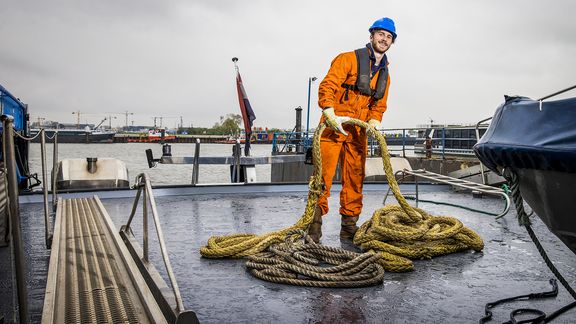 Boy Stolk met touw in zijn hand aan het werk op een schip