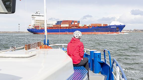 Passagier op schip kijkt naar containerschip