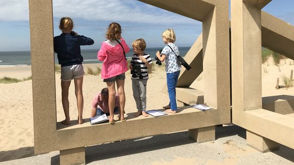 Kinderen staan in het monument De Zandwacht op Maasvlaktestrand