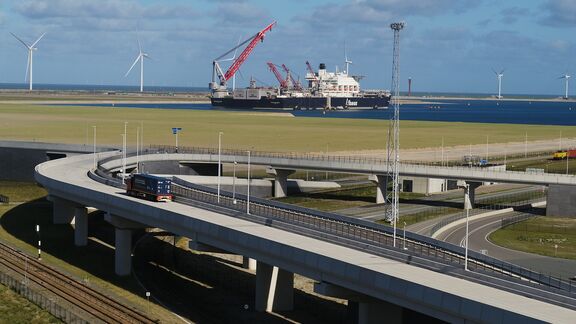 Vrachtwagen rijdt over de Container Exchange Route met de Pioneering Spirit op de achtergrond