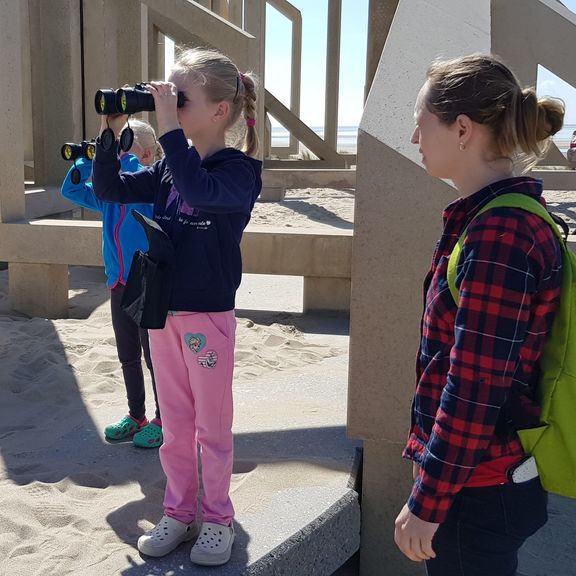 A girl looks at the ships with binoculars