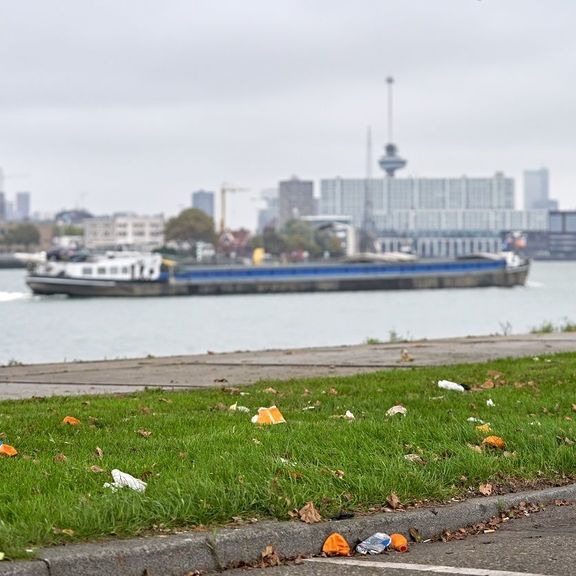 Barge in the Waalhaven in Rotterdam with a grass field with litter in the foreground