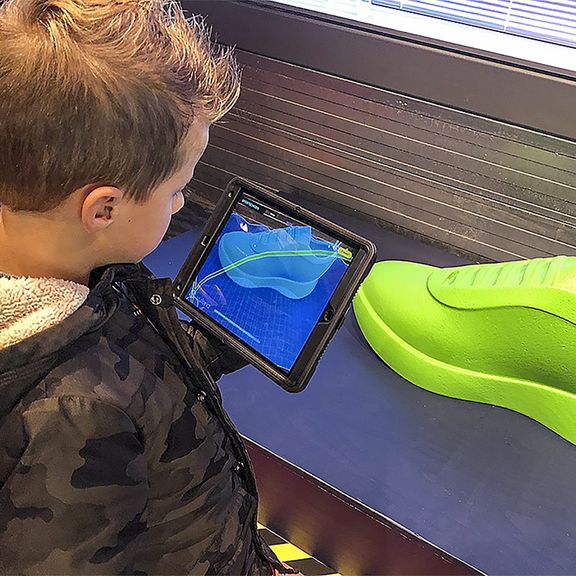 Kind met tablet in de hand bekijkt het transport van die sportschoen van China naar Rotterdam