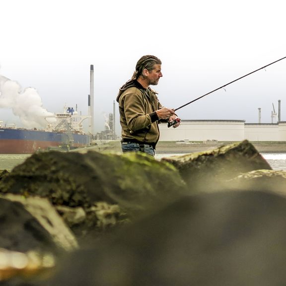 Man is aan het vissen in de haven