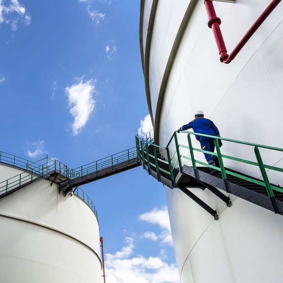 Mann klettert Treppe eines Tanks für die Lagerung von flüssiger Ladung