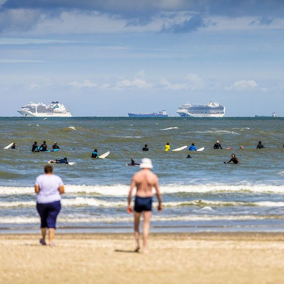 Schepen voor de kust met vakantiegangers op het strand