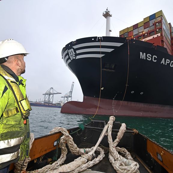 Oarsmen haul in the mooring lines of MSC Apolline