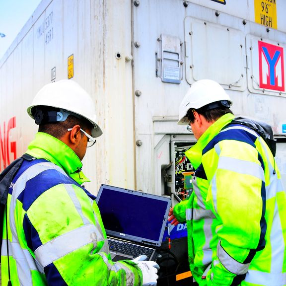 Two workers check a container