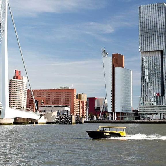 Watertaxi sails on the Nieuwe Maas in front of the Erasmusbridge