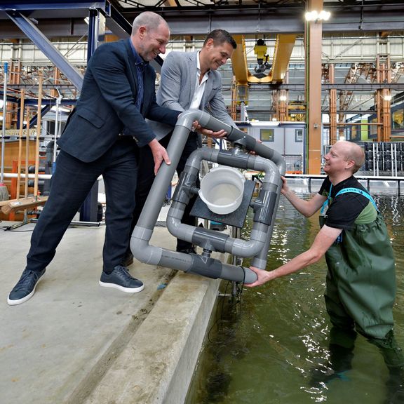 Onderzoeker en aquarist Sander van Lopik toont het drijvende kweeksysteem aan zijn directeur Erik Zevenbergen (links) en Richard van der Eijk (Havenbedrijf Rotterdam).