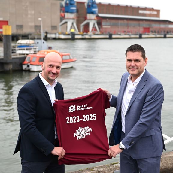 Martin den Ouden (links) en Richard van der Eijk tonen het nieuwe shirtje voor de Harbour Run aan de kade van de RDM Rotterdam