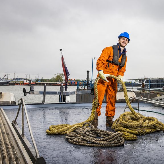 Boy Stolk met touw in zijn hand aan het werk op een schip