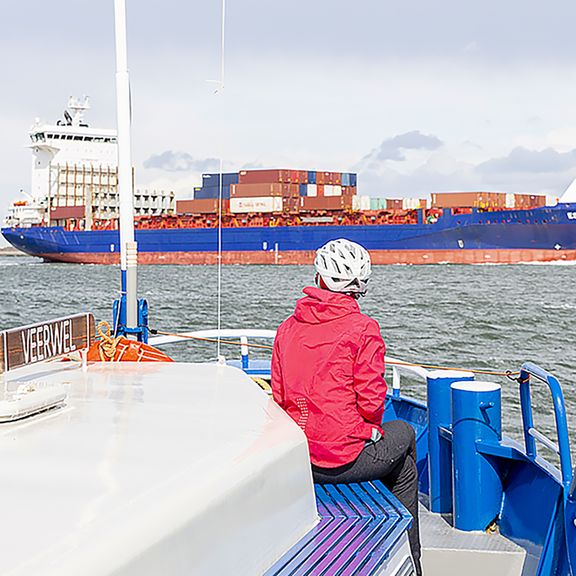 Passagier op schip kijkt naar containerschip