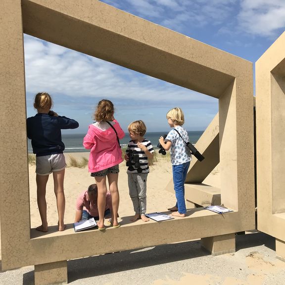 Kinderen staan in het monument De Zandwacht op Maasvlaktestrand