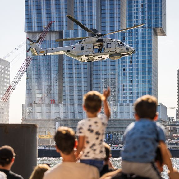 Kleine jongen op schouders vader zwaait naar voorbijvliegende helikopter tijdens Wereldhavendagen 2022