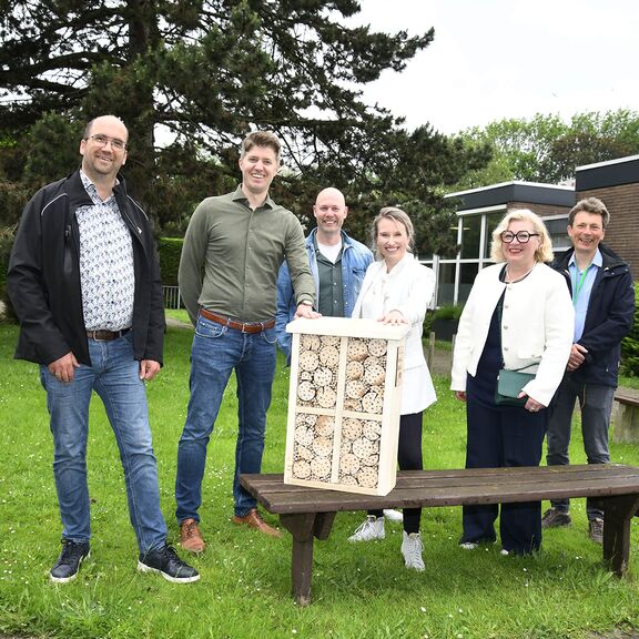 Deelnemers poseren met een bijenhotel bij een basisschool in Rozenburg