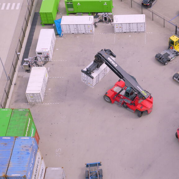 <meta charset="utf-8">Ein Reachstacker tauscht einen leeren gegen einen vollen ZES-Pack an der Ladestation in Alblasserdam aus.