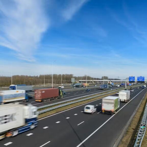Autobahn zwischen Maasvlakte und Vaanplein mit fahrenden Lastkraftwagen unter blauem Himmel.”