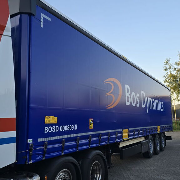 Blauwe Bos Dynamics-vrachtwagen op parkeerterrein.